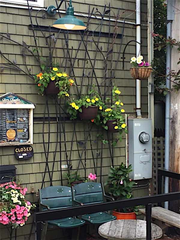 Custom metal trellis with hanging containers of yellow and orange black-eyed Susan